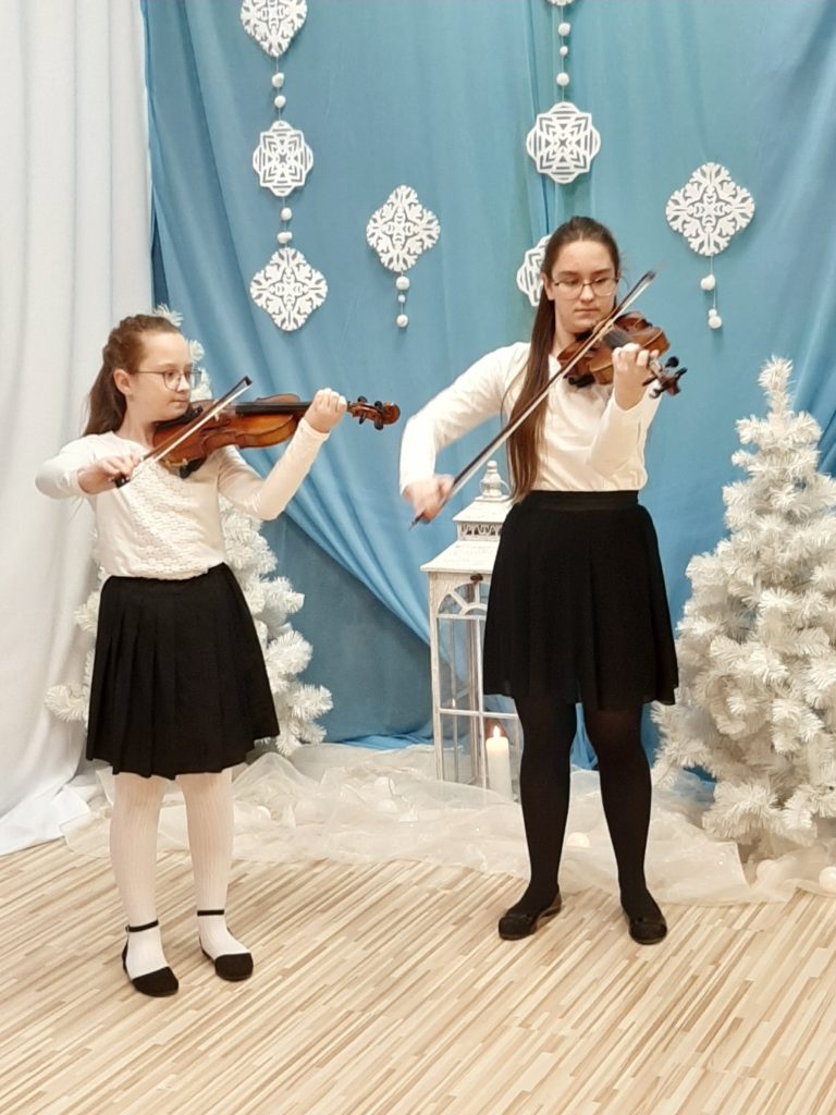 dziewczynki grające na skrzypcach na tle dekoracji